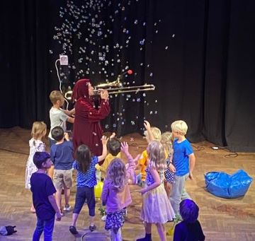 Barn interagerar med Elias som blåser såpbubblor med en trombon